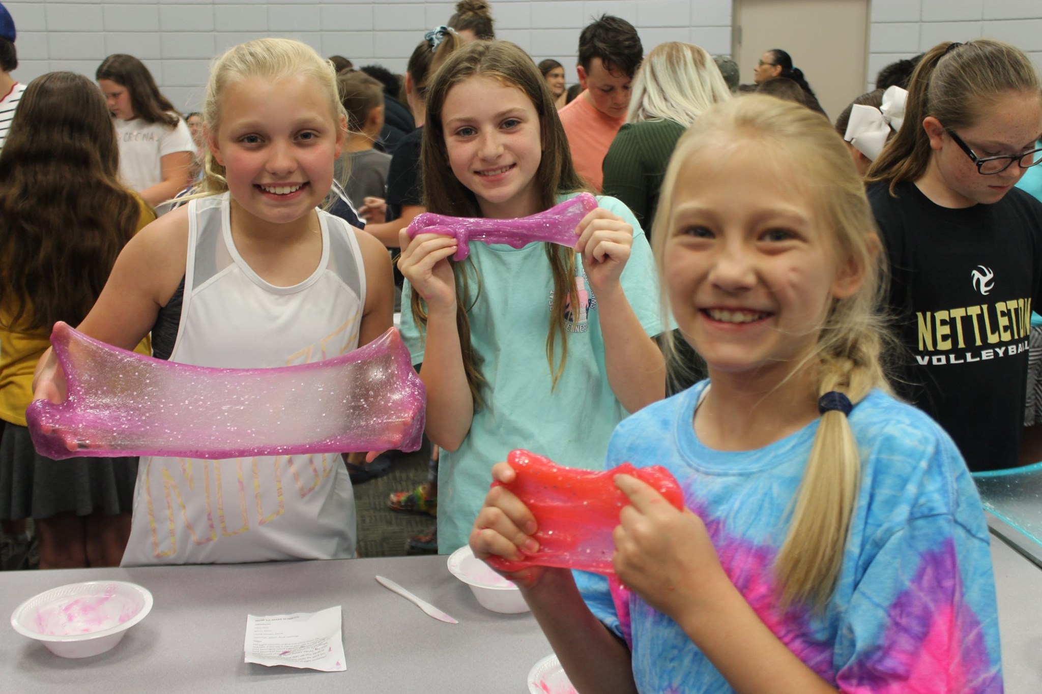 Three tween girls proudly display the slime they made at an event in the Round Room